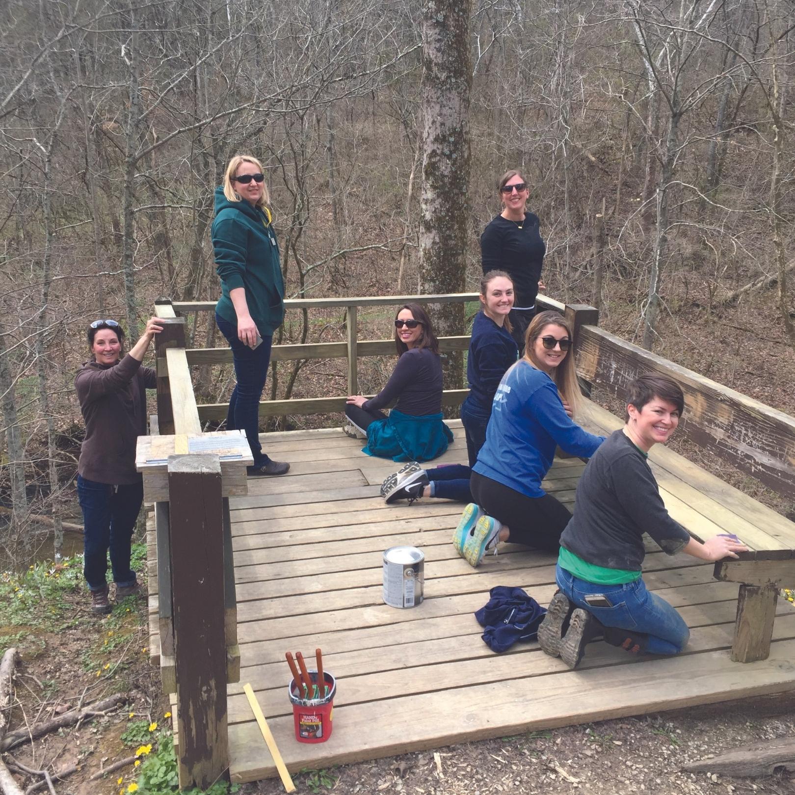 A group of young women working on finishing a wooden overlook in the woods